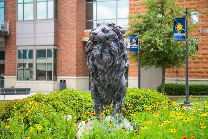 在A大学校园的基座上，一尊春花盛开的狮子雕像&移动商务.